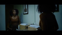 a woman in a brown top standing in front of a mirror